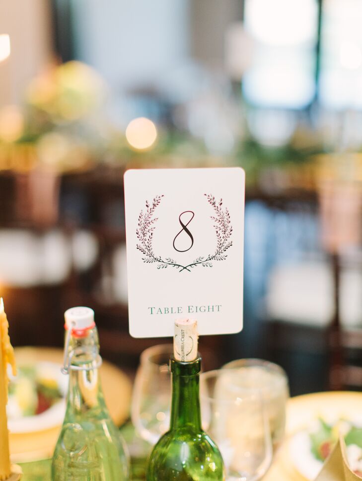 Ann and her family collected several green glass wine bottles months before the wedding, and they used the corks to hold up table numbers decorated with wreath designs.