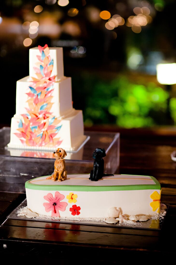 The couple set out two cakes: a square-tiered one with colorful petals, and a surfboard one with replicas of their two dogs on top.