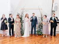 Bride and groom champagne toasting with wedding party during speech at wedding reception.