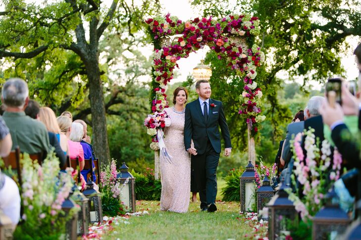 Paige and Matt went all out for their ceremony flowers. They said "I do" under a wedding arch covered in bold and bright pink blooms. Lanterns, pink and white flowers and flower petals lined the grass aisle.