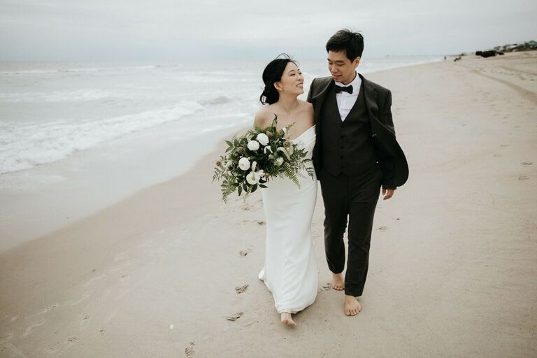 Couple walking down the beach in formal wedding attire