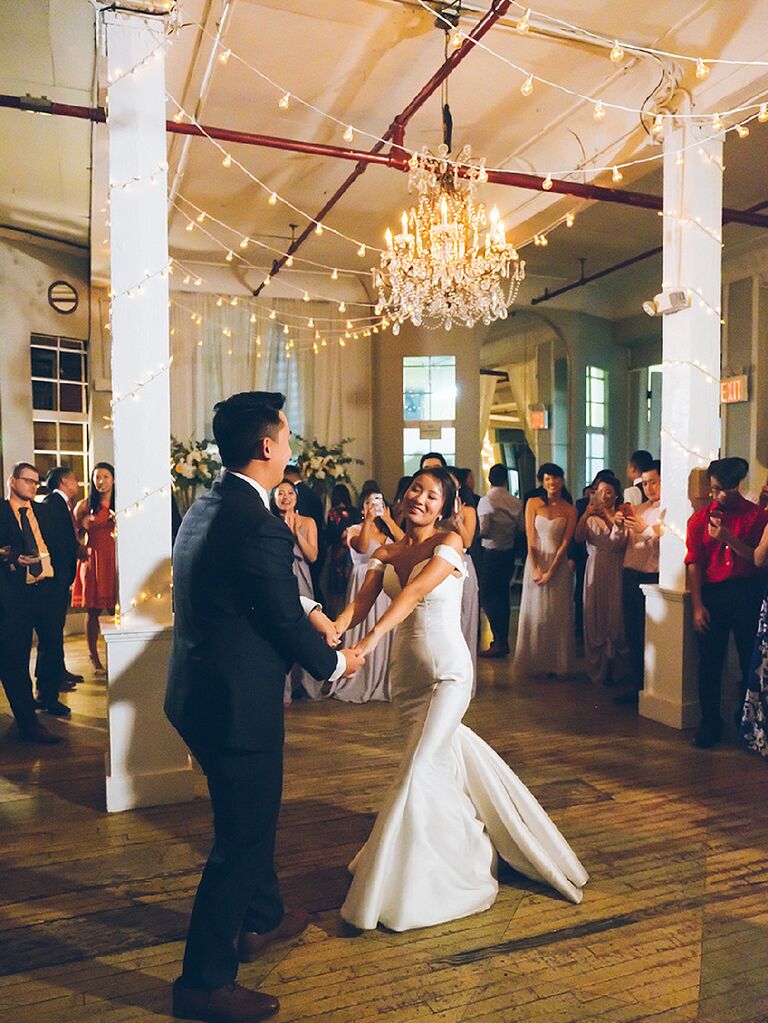 Bride and groom dancing under vintage chandelier and string lights