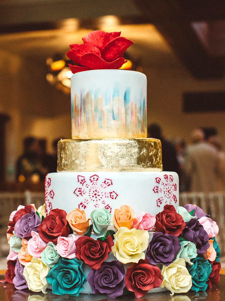 Multicolor rose decorated wedding cake with watercolor designs and gold foil