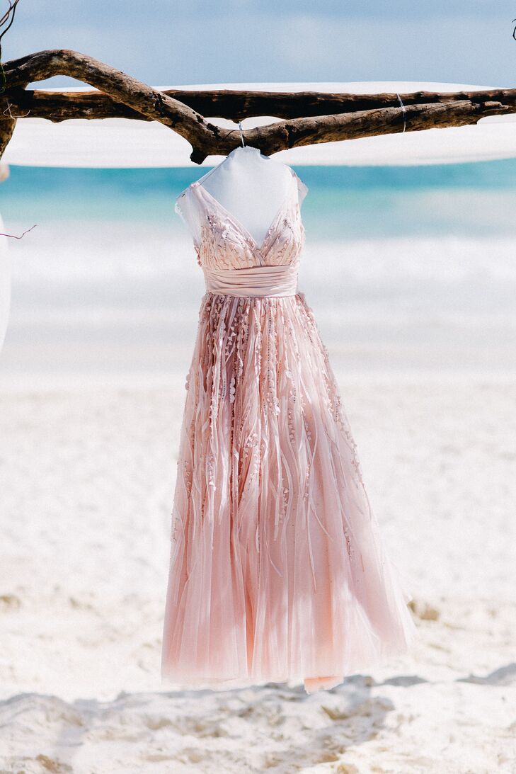 Danielle wore an incredible blush wedding dress with a low V-neck and sequin accents trailing down the flowy, ethereal skirt. The Watters Soledad dress matched the wedding's romantic, beachy vibe.
