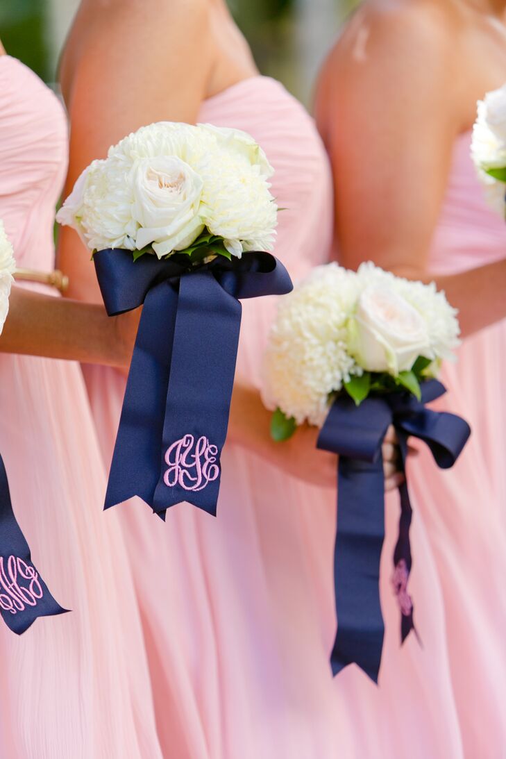 For the bridesmaids bouquets, they left the entire design up to Signature Florals. Each one was filled with off-white roses and white peonies for a timeless look. But what made the bouquets extra special were the wraps. Navy bows brought every stem together and included this chic pink monogram so every bridesmaid knew exactly which white bouquet belonged to whom.