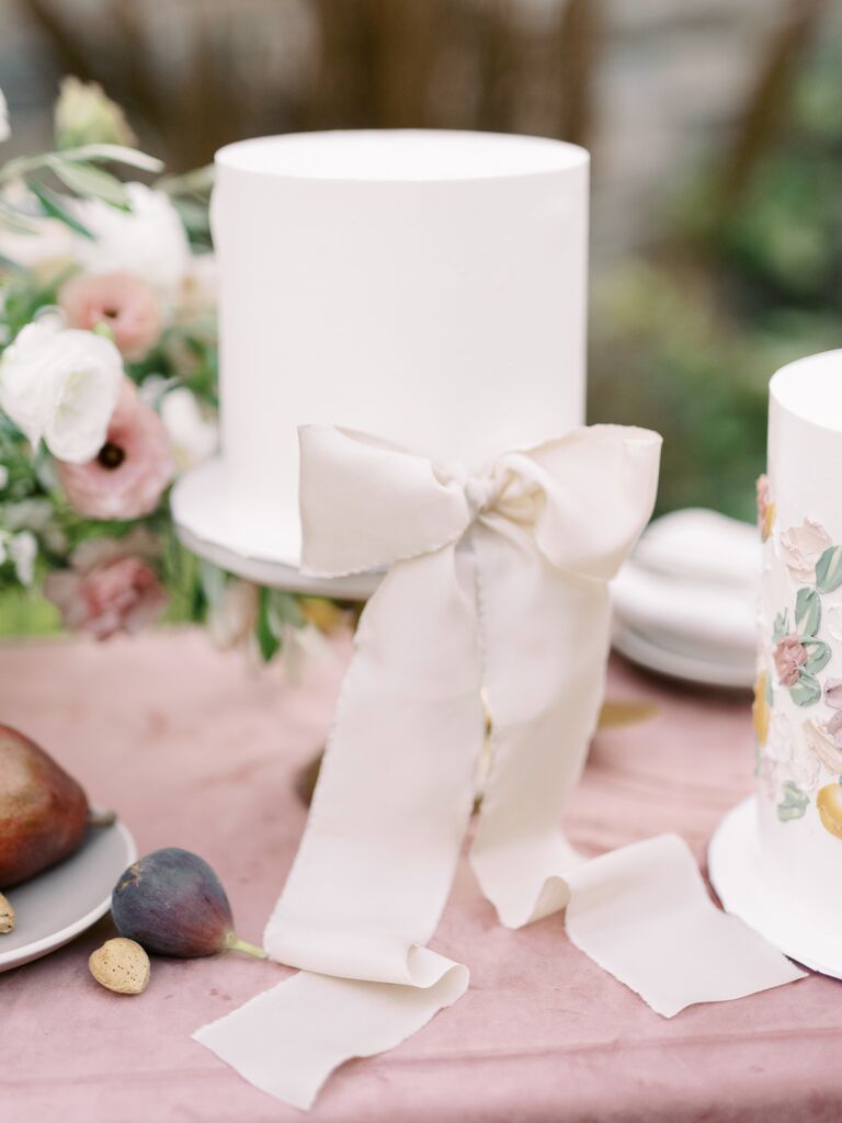 white fondant one tier wedding cake with ivory satin bow at the base
