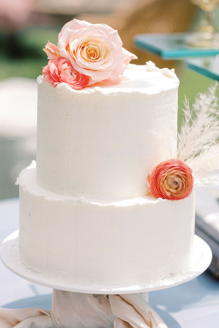 White two-tier wedding cake with fresh flowers
