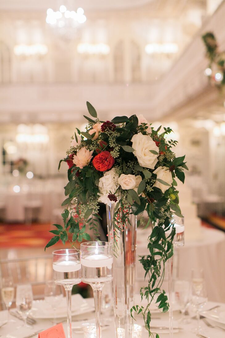 This tall centerpiece arrangement had pink and red roses along with cascading eucalyptus leaves down the side of the clear, cylindrical vase.