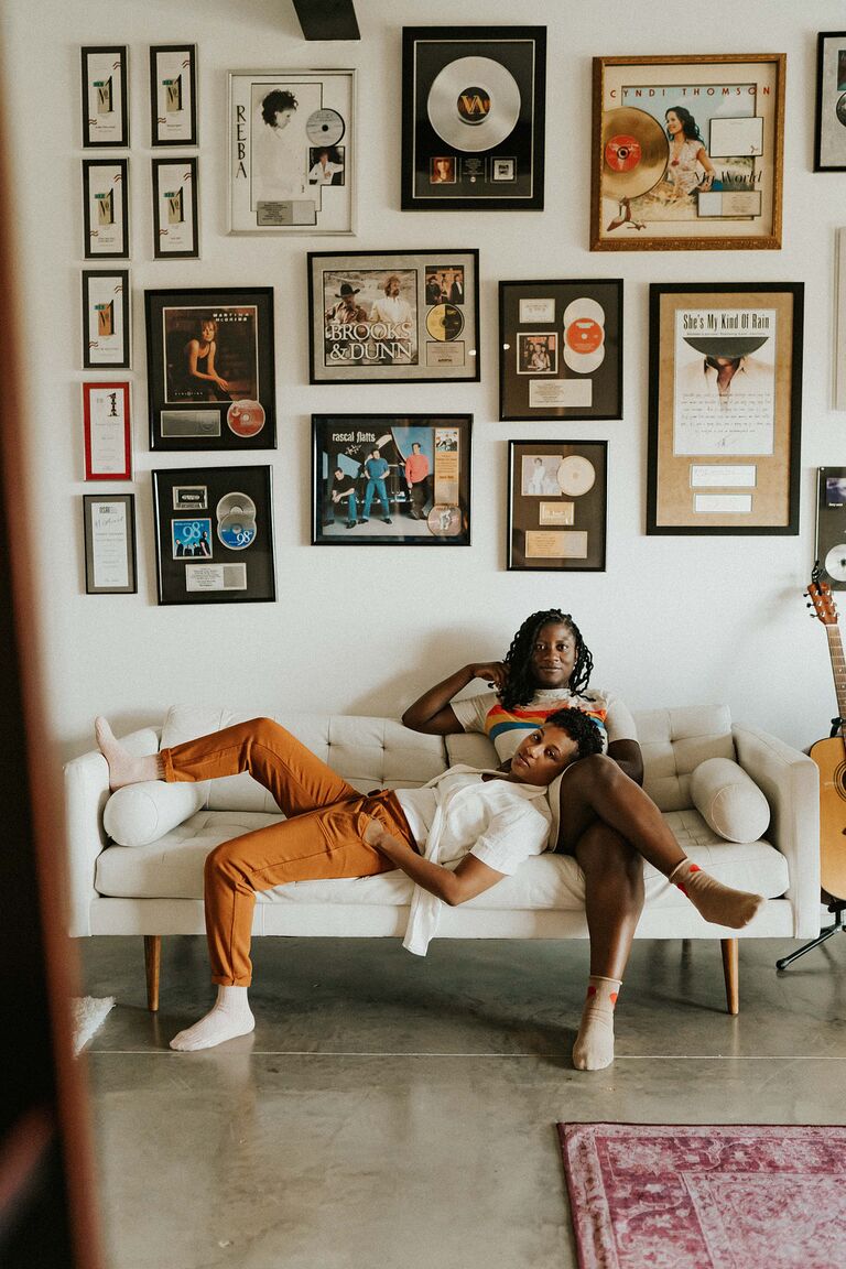 Same-sex couple relaxes on couch surrounded by vinyl records