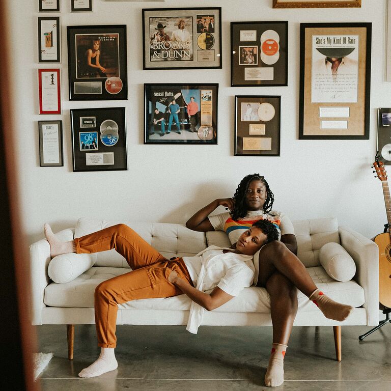 Same-sex couple relaxes on couch surrounded by vinyl records