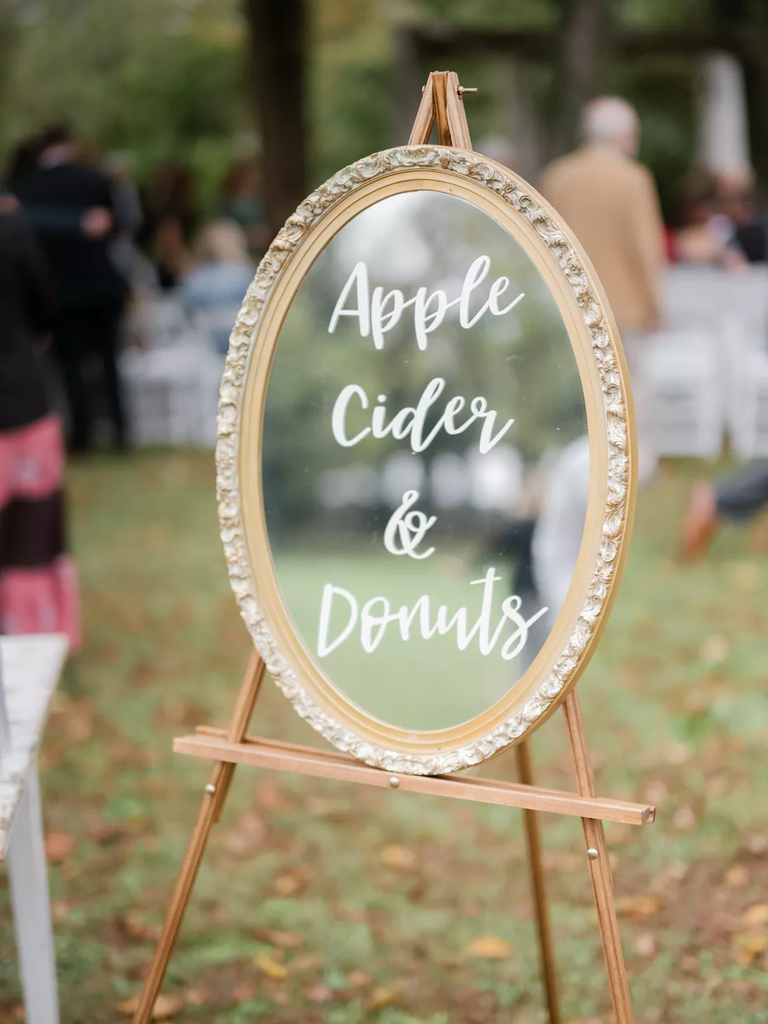 A mirror sits on a wooden easel, with chalk writing declaring what's for offer at the sweets table.