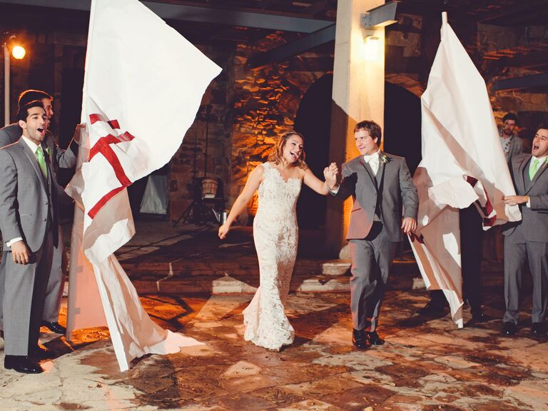 Bride and groom walk through paper banner. 