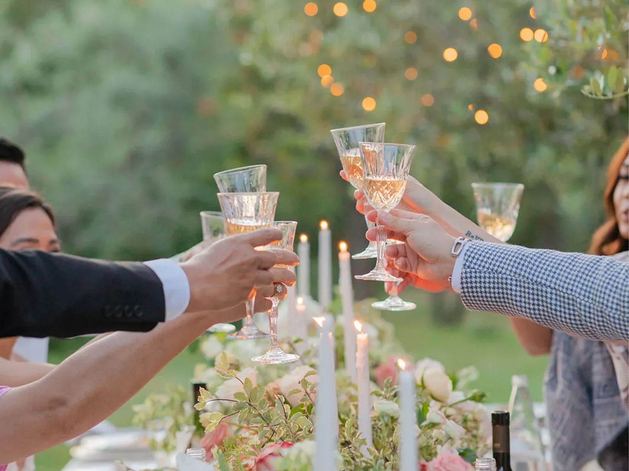 Group cheering wine glasses at dinner table.