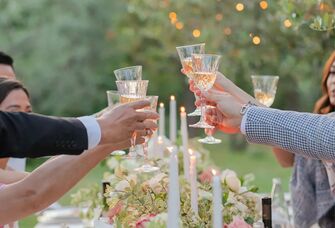 Group cheering wine glasses at dinner table.