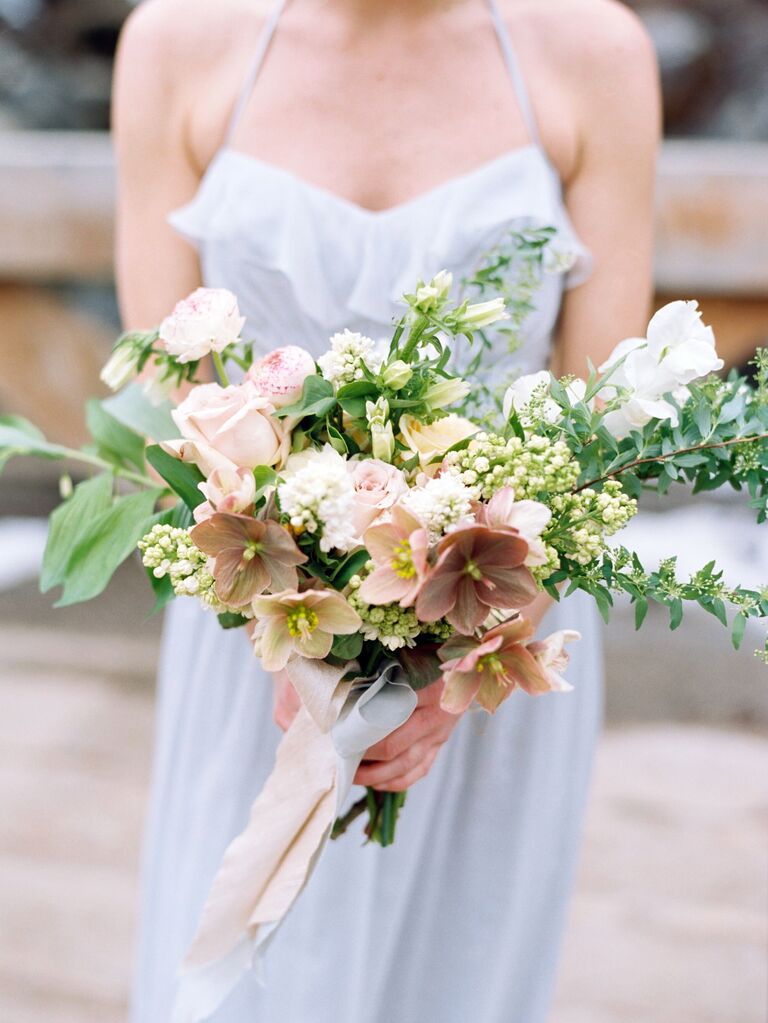 A bride holds this peach-toned bouquet.