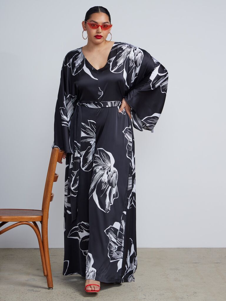 Model wearing a stylish floral jumpsuit with v-neckline, flowing sleeves and wide-legged pants.