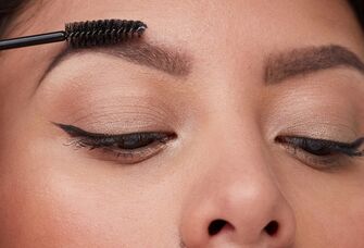 Person using a spoolie brush to comb their eyebrows