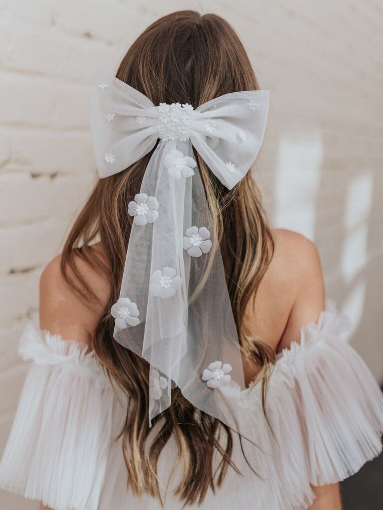 Model wears sheer bow with floral embellishments. 