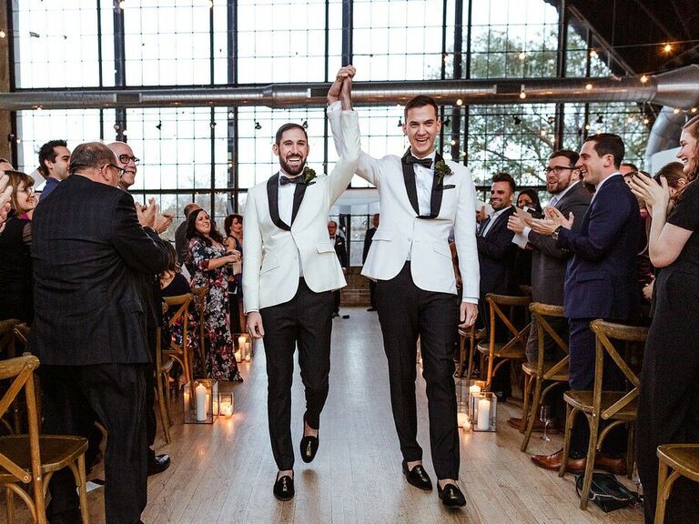 Couple holding hands in air down the aisle