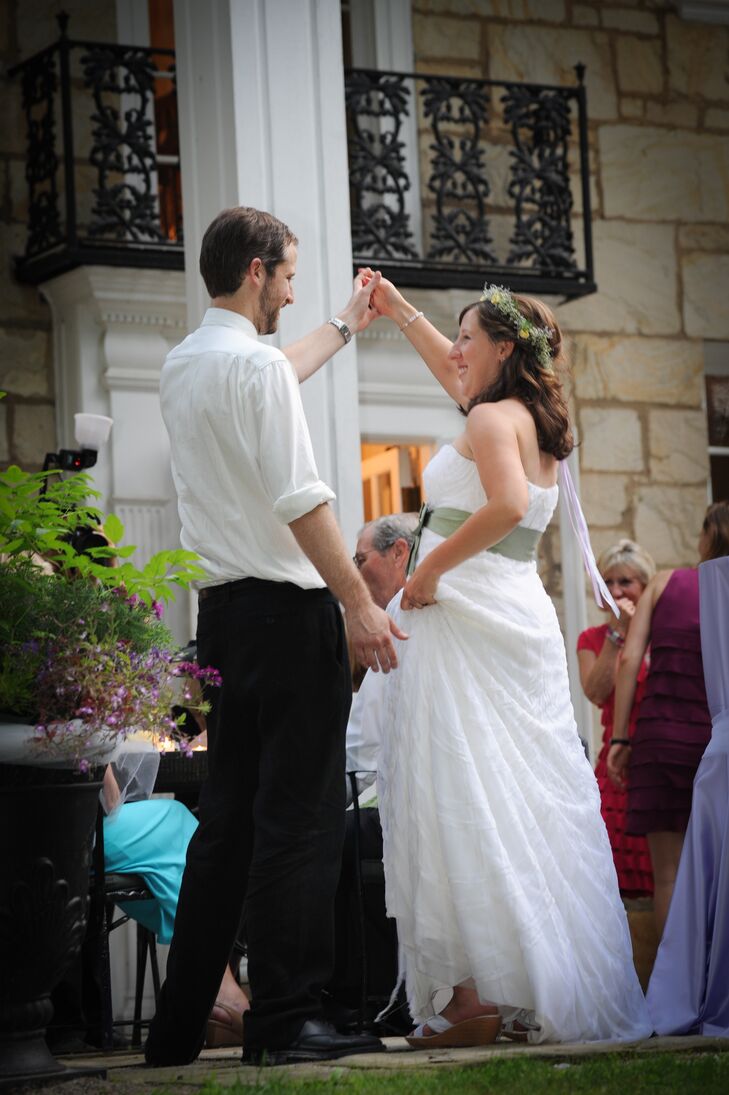 Christine wore a flower crown made of yellow roses and baby's breath on her wedding day, which complemented the natural look of her ivory wedding dress accented with a sage green sash. For their first dance, Mike took off his black suit jacket and wore his white-collared dress shirt with the sleeves rolled up.
