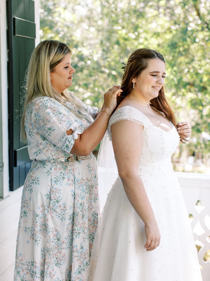 During the getting ready process, the mother of the bride helps the bride with a necklace gifted to her mother by her father as her "something blue."