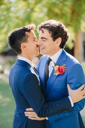 Grooms in Suits in Different Shades of Blue, Bright Coral and Pink Boutonnieres Embracing