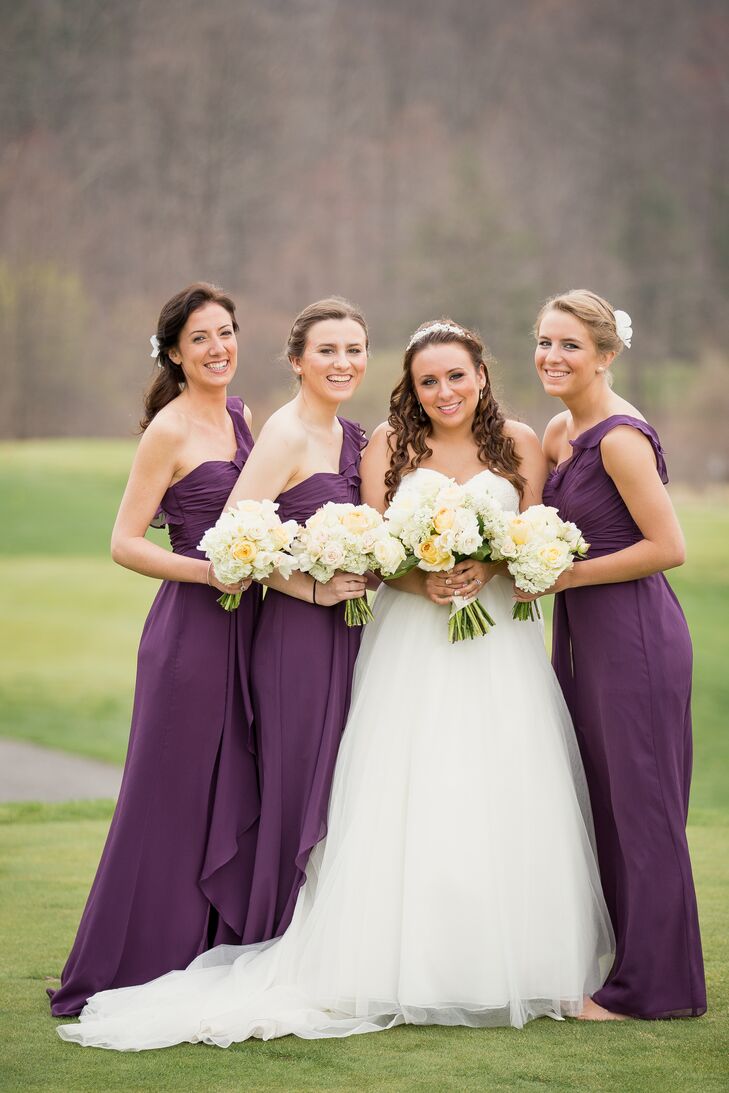 With Sarah's favorite color in mind, each bridesmaid wore a floor-length eggplant dress from David's Bridal for the wedding. A ruffle detail on the skirt and one-shoulder strap added a fun accent to the gown as each woman wore her hair in either an updo or side-swept hairstyle with a white accent.