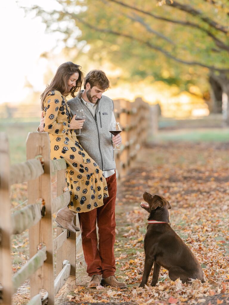 To-be-weds looking at their dog while drinking wine.
