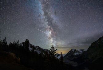 A night sky with the Milky way and shooting star over mountains at Peyto Lake, Banff national park, Alberta, Canada
