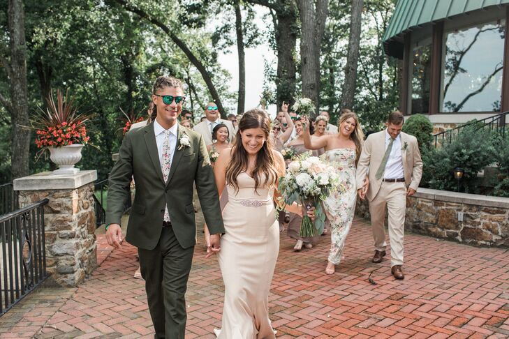 Groom Wearing Green Suit, Bride in Formfitting Gown, and Wedding Party in Neutral Attire