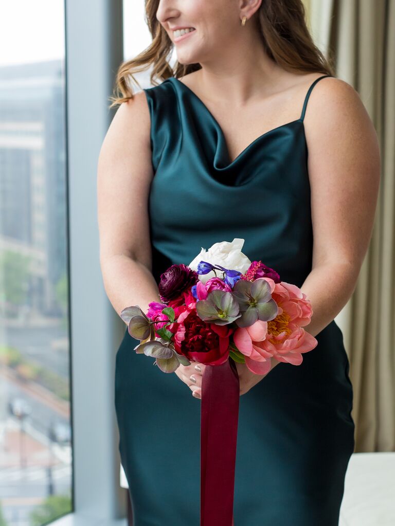 bridesmaid wearing emerald green slip dress holding bouquet with magenta flowers