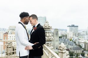 Grooms in White Jacket and Black Velvet Jacket Embracing on Balcony Overlooking San Francisco