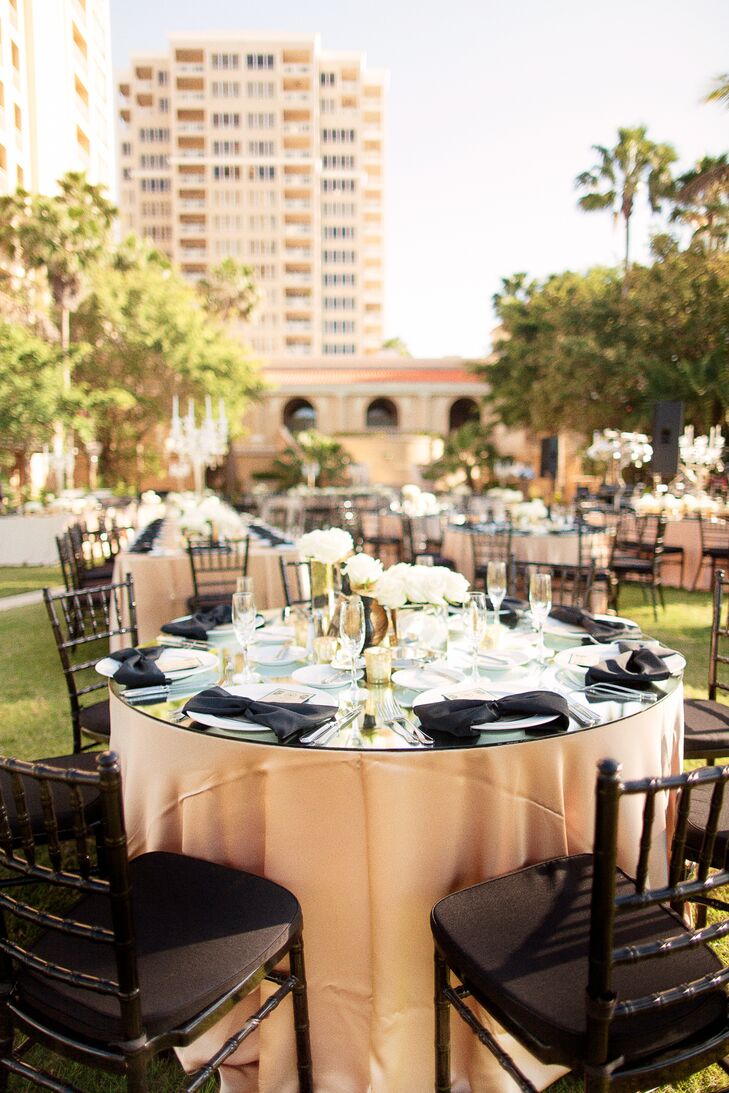 Each glass topped round table was met with gold linens, a white floral centerpiece with rose or hydrangeas, gold accents and an Art Deco style table number to match their Great Gatsby inspiration.