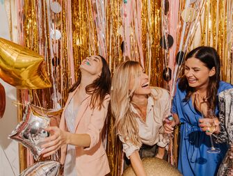 Group of women laughing in front of backdrop at bridal shower
