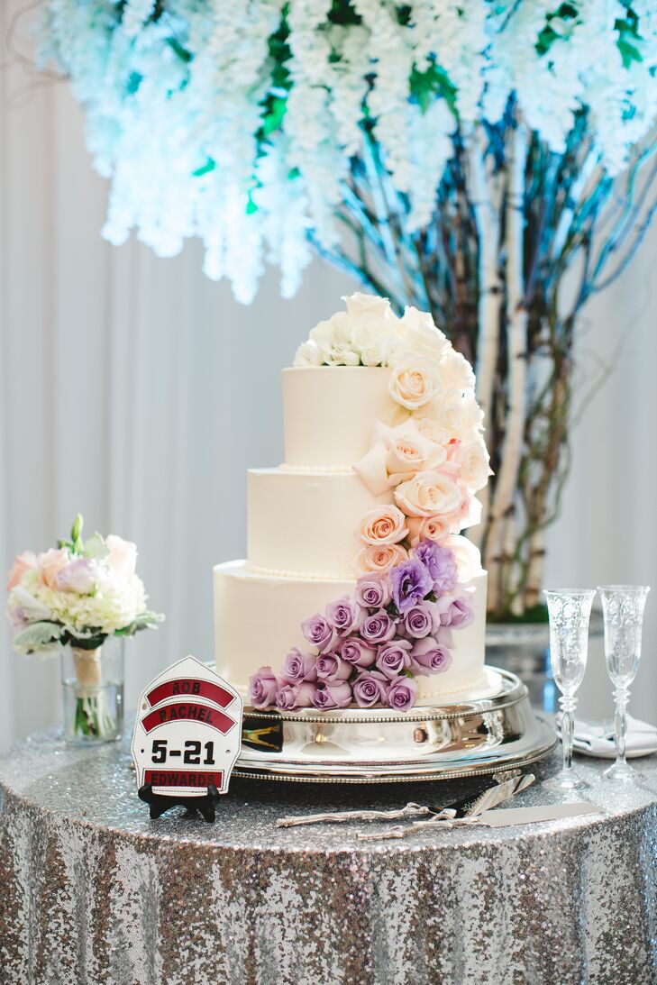 The couple’s three-tier cake was frosted in Swiss buttercream and incorporated two kinds of cake flavors: vanilla genoese with lemon and raspberry mousse for Rachel and red velvet for Rob. The cake was topped with cascading blooms in white, pink and purple. “Instead of a cake topper, we opted for a custom firefighter helmet shield with our names and wedding date in homage to Rob’s job,” Rachel says.
