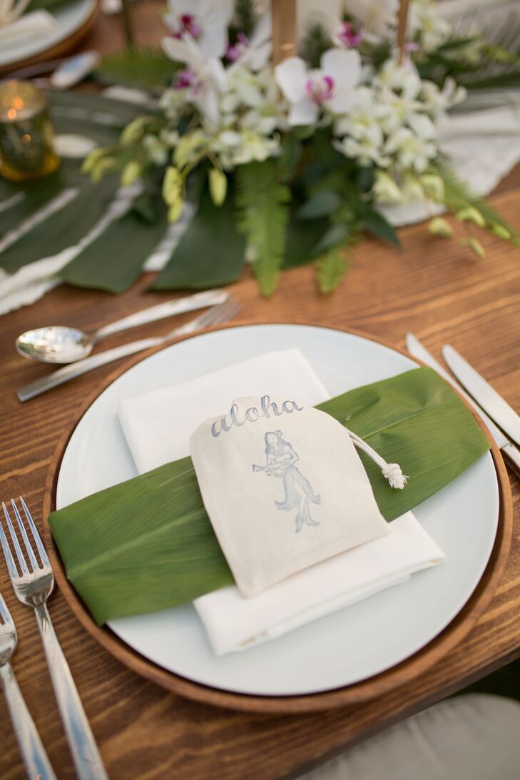 The banquet table was topped with fern fronds and pineapples. Each table setting included a menu handwritten in gold calligraphy on large leafs as well as a small Hawaiian-themed favor.