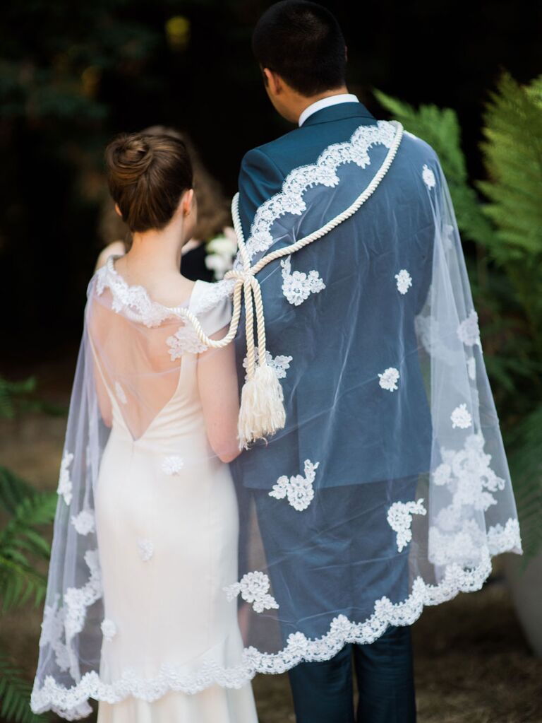 Bride and groom wearing veil and rope during traditional Lasso ceremony