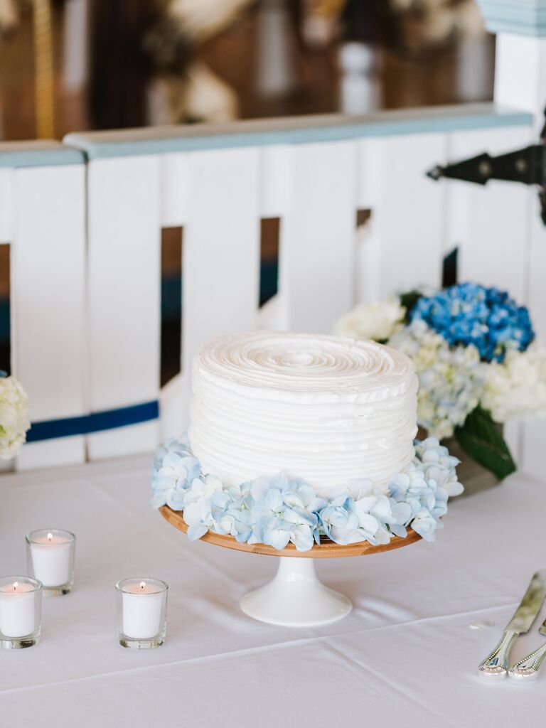 classic one tier wedding cake with white buttercream frosting and blue hydrangeas