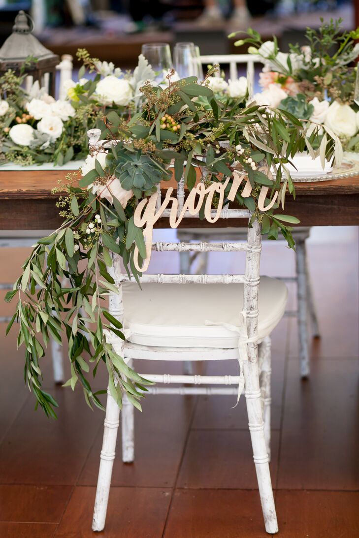 Rebecca and James decided against a sweetheart table, but Dragonfly Events made sure their seats stood out: draped in cascading garlands of eucalyptus and whimsical bride and groom signs.