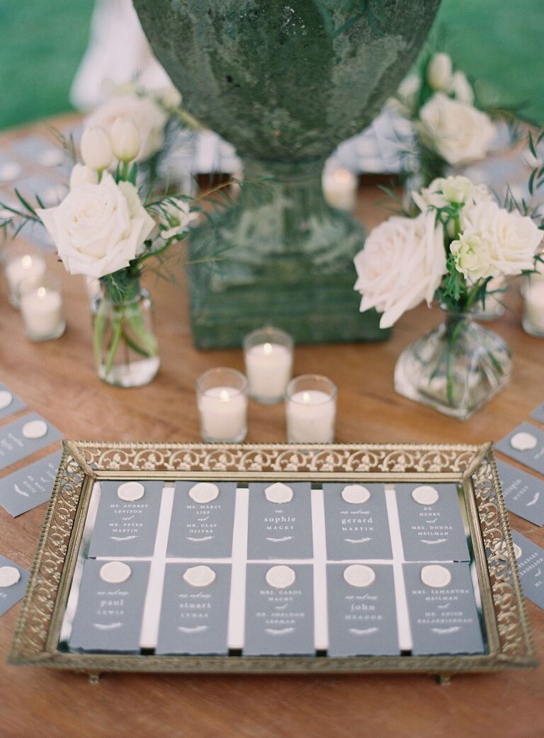 Gray escort cards with white wax seal on vintage gold mirrored tray