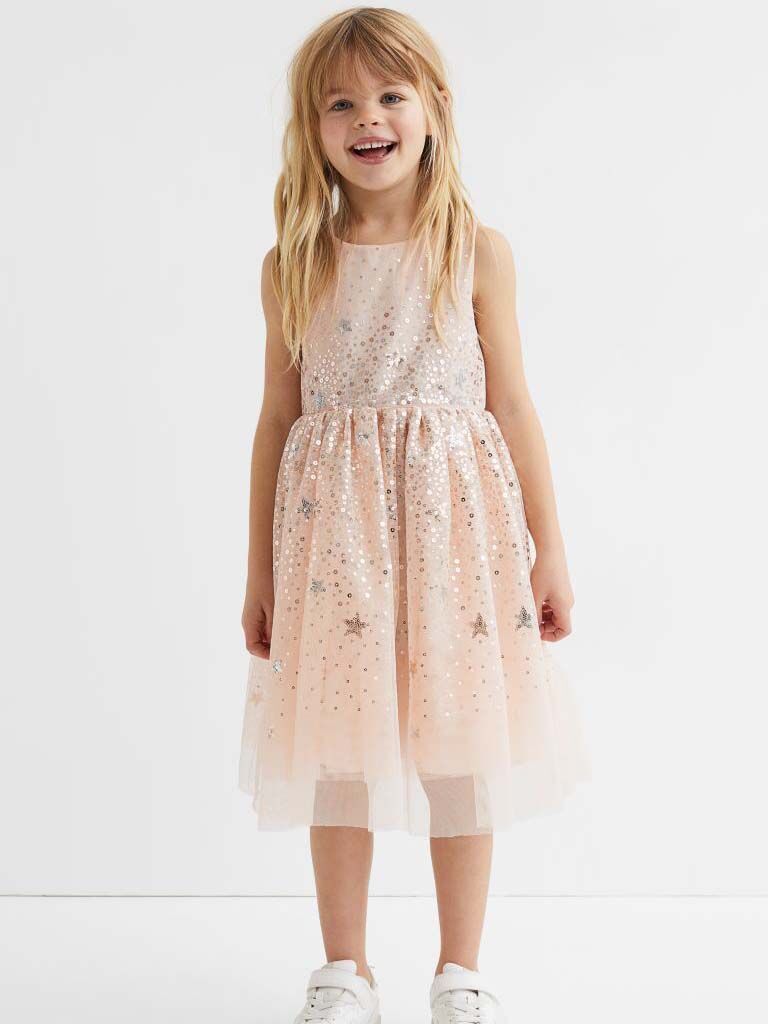 little girl wearing beige dress with gold stars