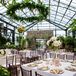 With linen tablecloths, brown chiavari chairs, tall floral arrangements and lush greenery, the overall vibe of the reception was that of a sophisticated garden party. The glass ceiling—showcasing the sky—added to the feeling of being outdoors.