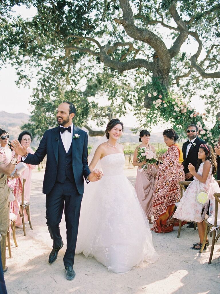 The happy couple walk down the aisle at their outdoor vineyard wedding