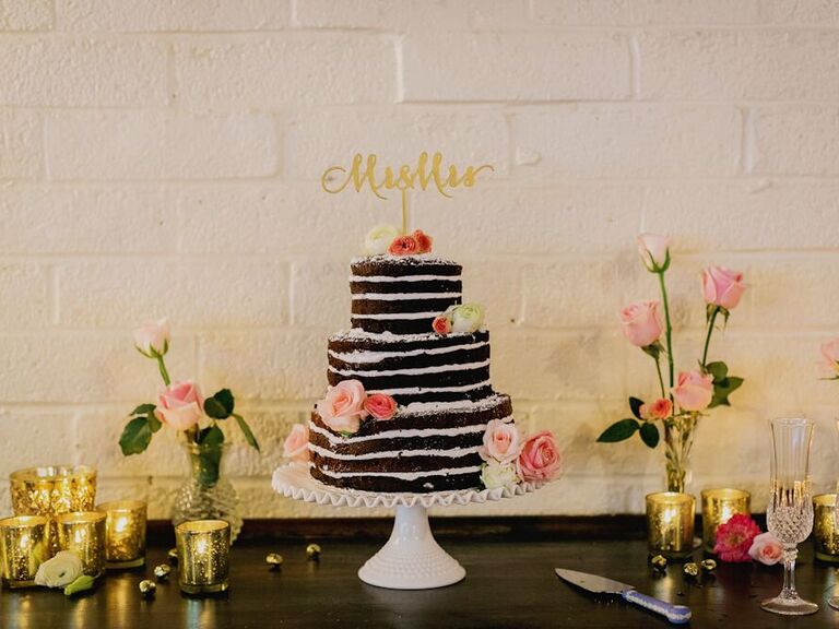 three tier chocolate naked wedding cake with pink and ivory roses and gold mr & mrs. cake topper