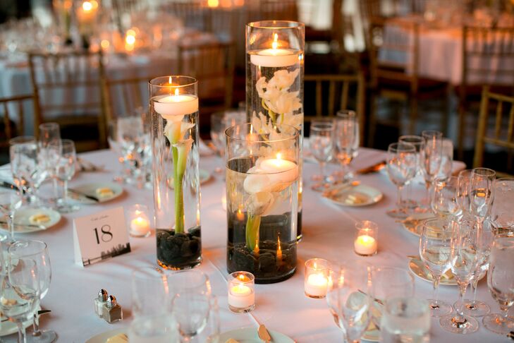 Hurricane vases filled with black river stones, ivory calla lilies and orchids and floating candles added a modern, romantic touch to each of the reception tables.