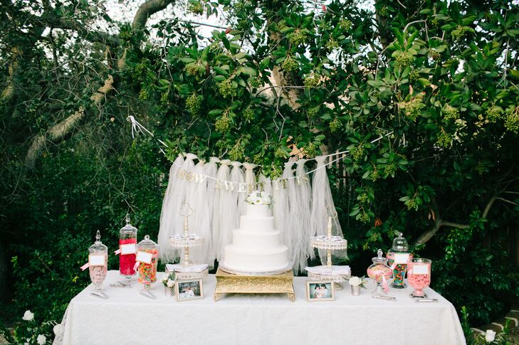 The bride and groom had a traditional four-tier white wedding cake topped with seasonal white flowers. On the side, they had a candy bar filled with their favorite candies and pictures of them as children.