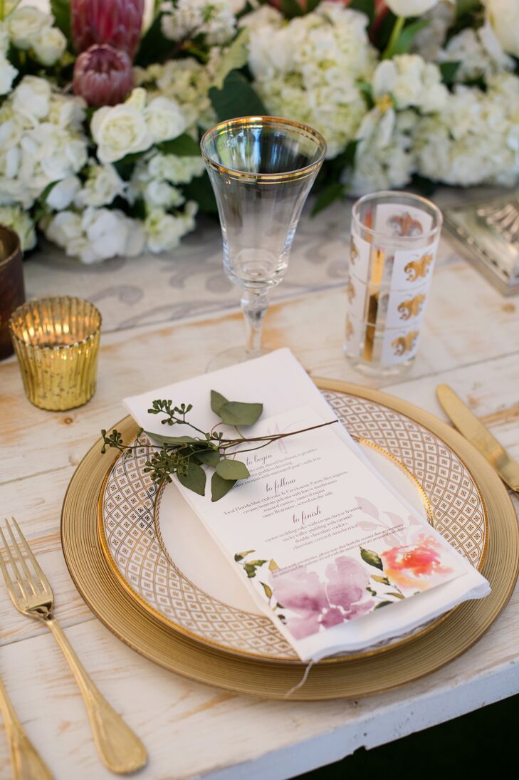 The menu cards doubled as the place cards, with the names of each guest hand calligraphed in playful pink ink. Bearing bright watercolor flowers, they added a pop of color to the stately patterned plates, gold chargers and cutlery.
