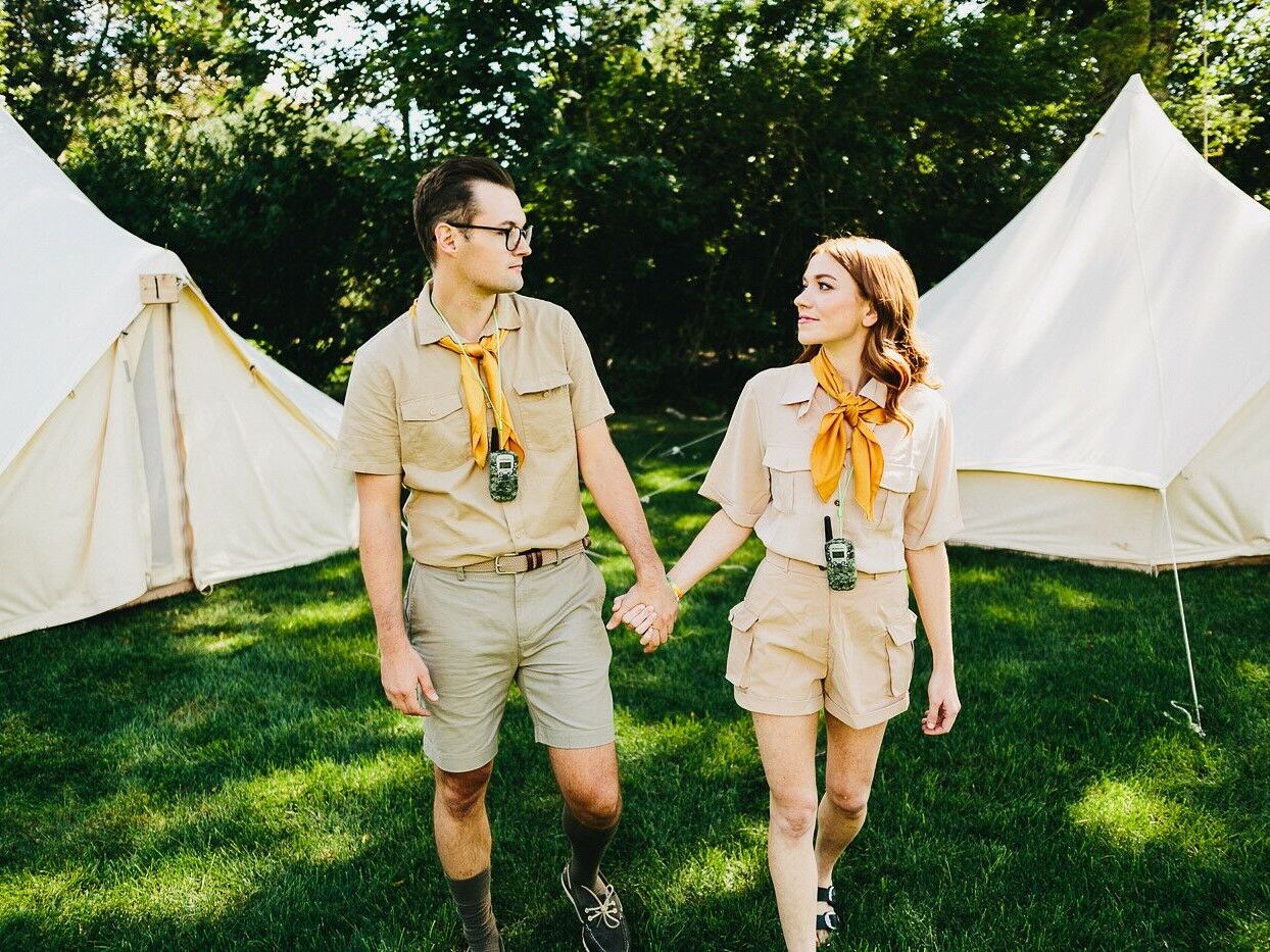 Couple holds hands while wearing summer camp gear. 