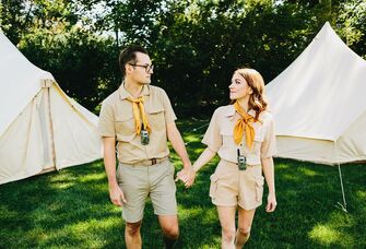 Couple holds hands while wearing summer camp gear. 