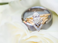 Diamond engagement ring sitting atop a silver wedding band.